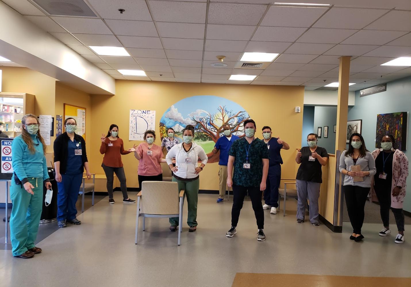 Members of a health care team wearing face masks stand together inside a health center.