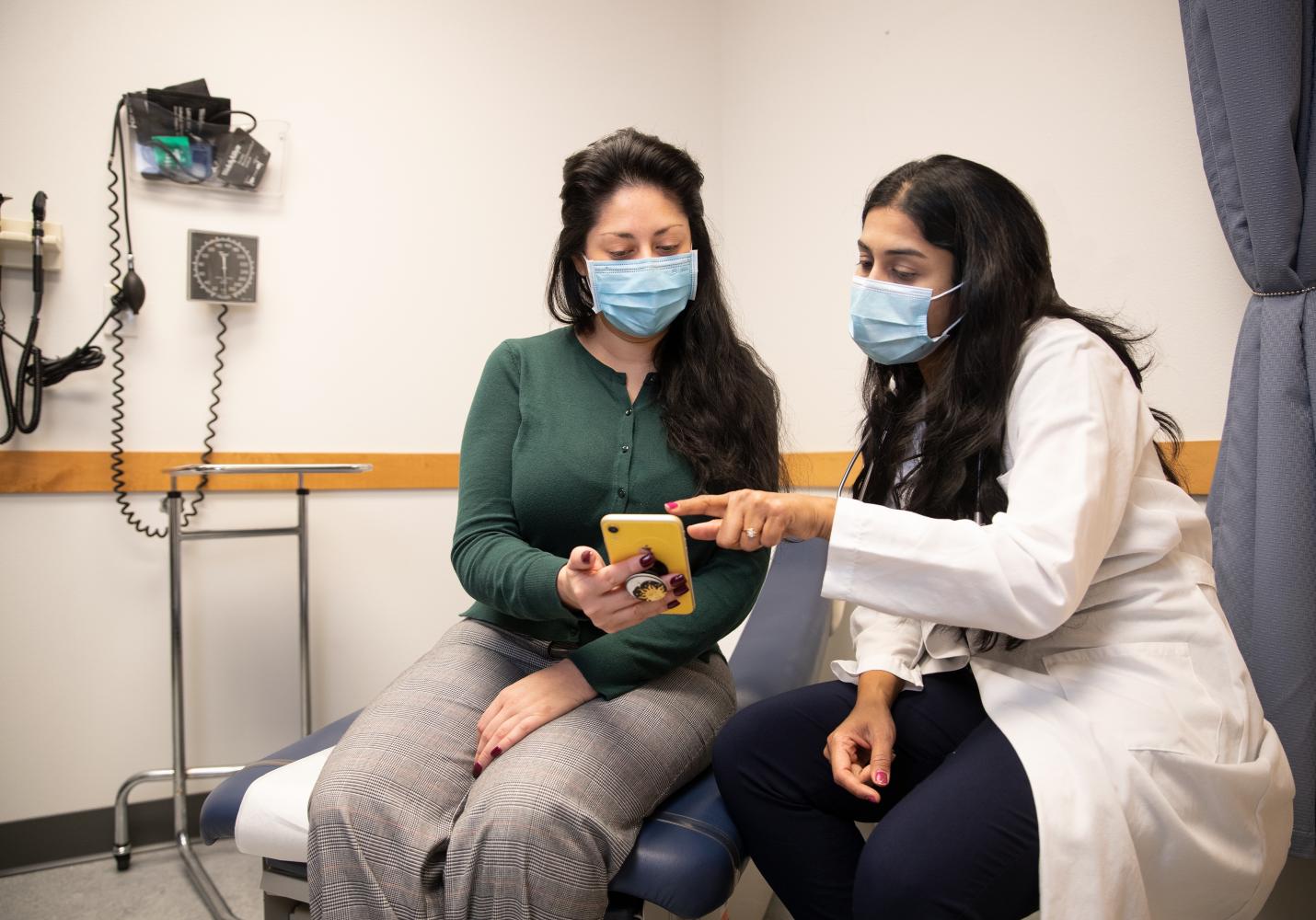 A doctor shows a patient how to use Multnomah County MyChart on a smartphone.
