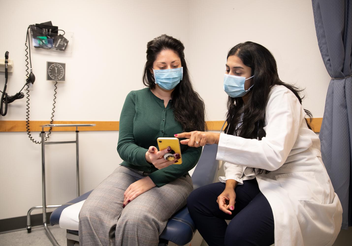 A doctor shows a patient how to use MyChart on a smartphone.
