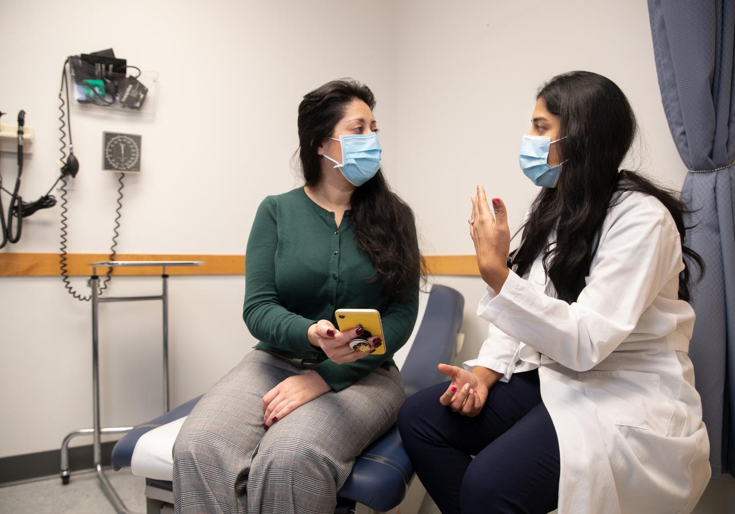 A doctor talks with a patient in an examination room.