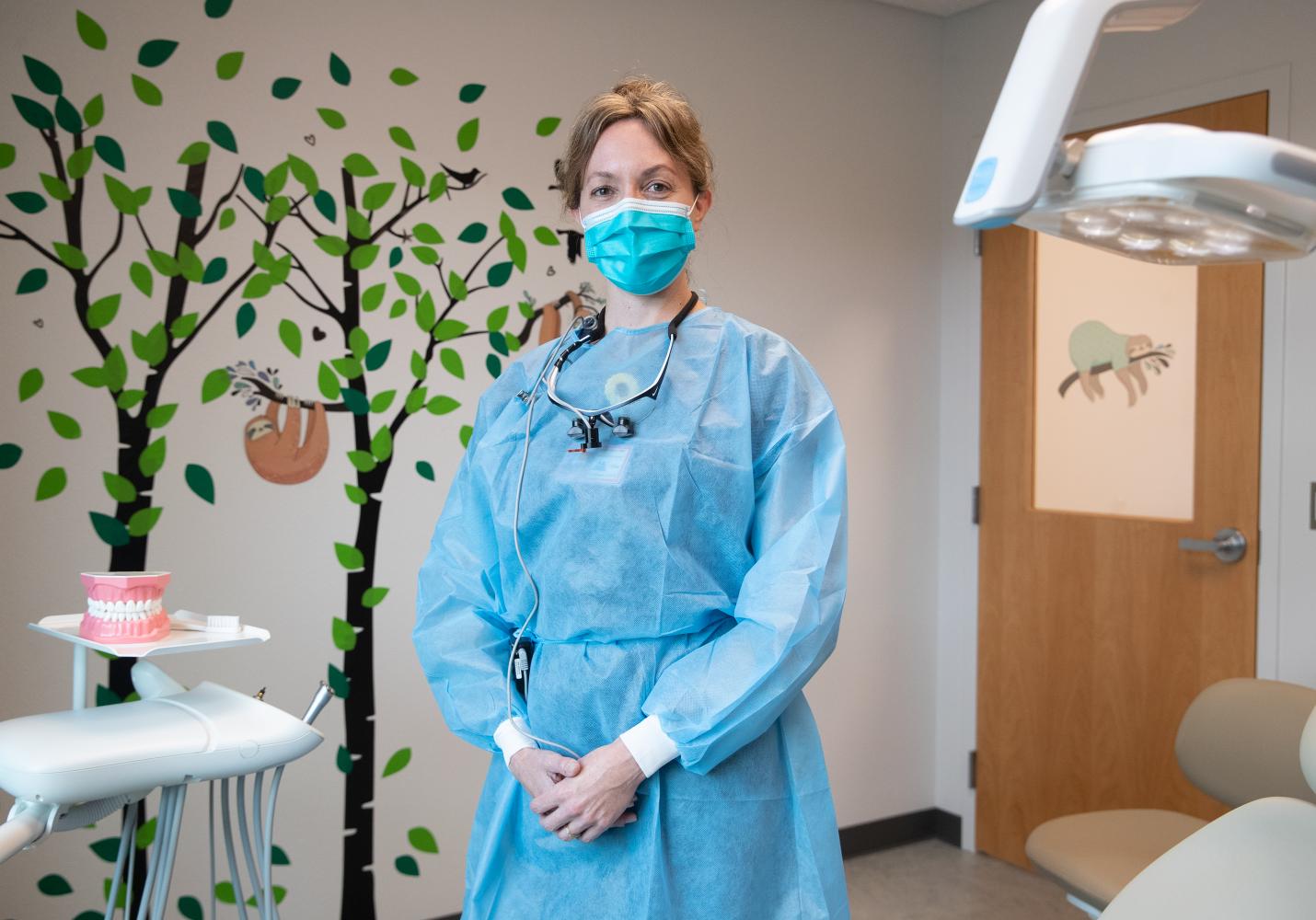 A dental care team member stands in an examination room at a dental clinic.
