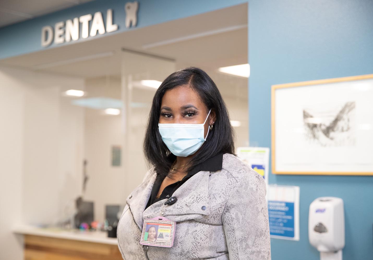 A dental care team member stands near the front desk of a dental clinic.