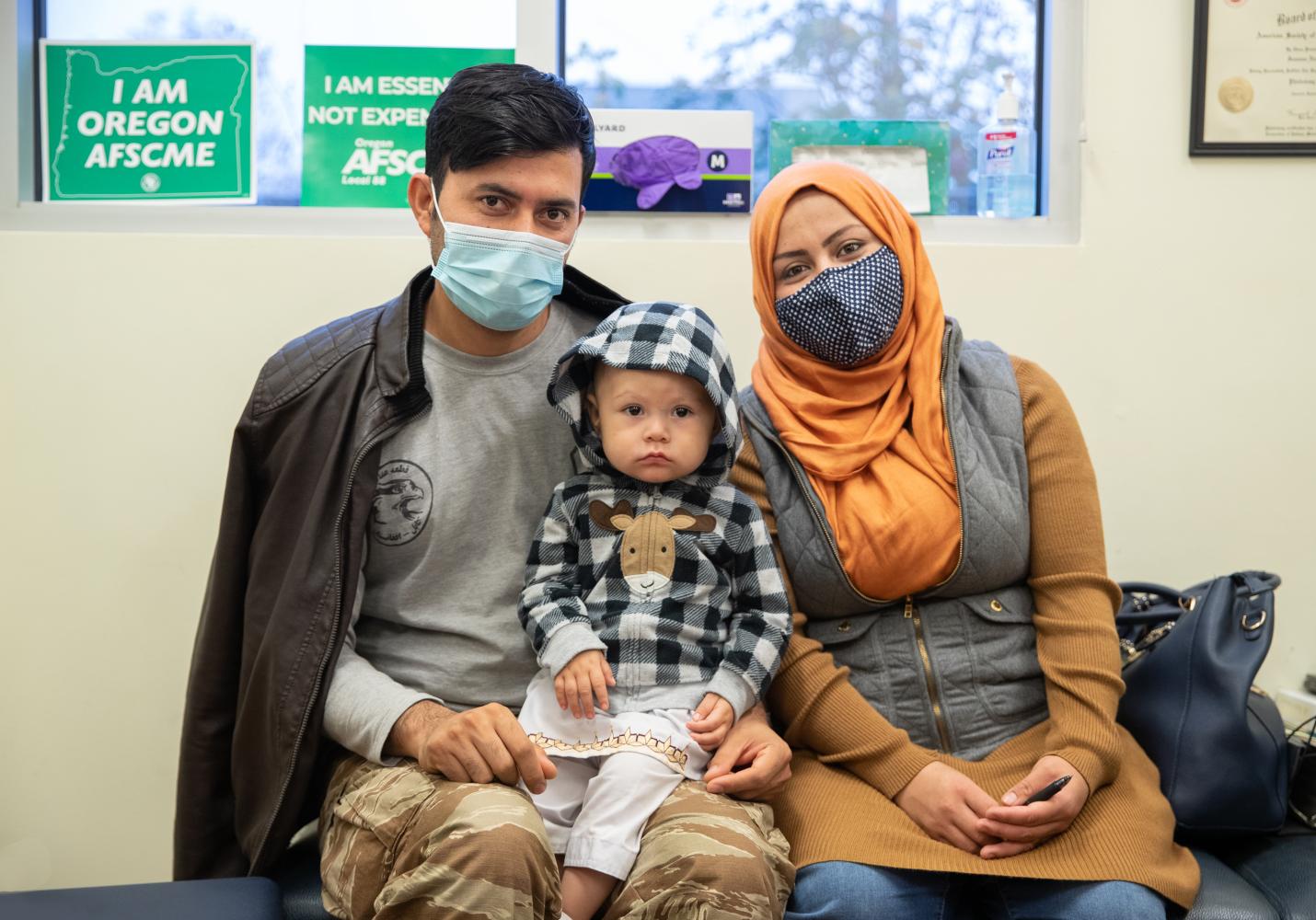 A mother, father, and baby sit together at their health center.