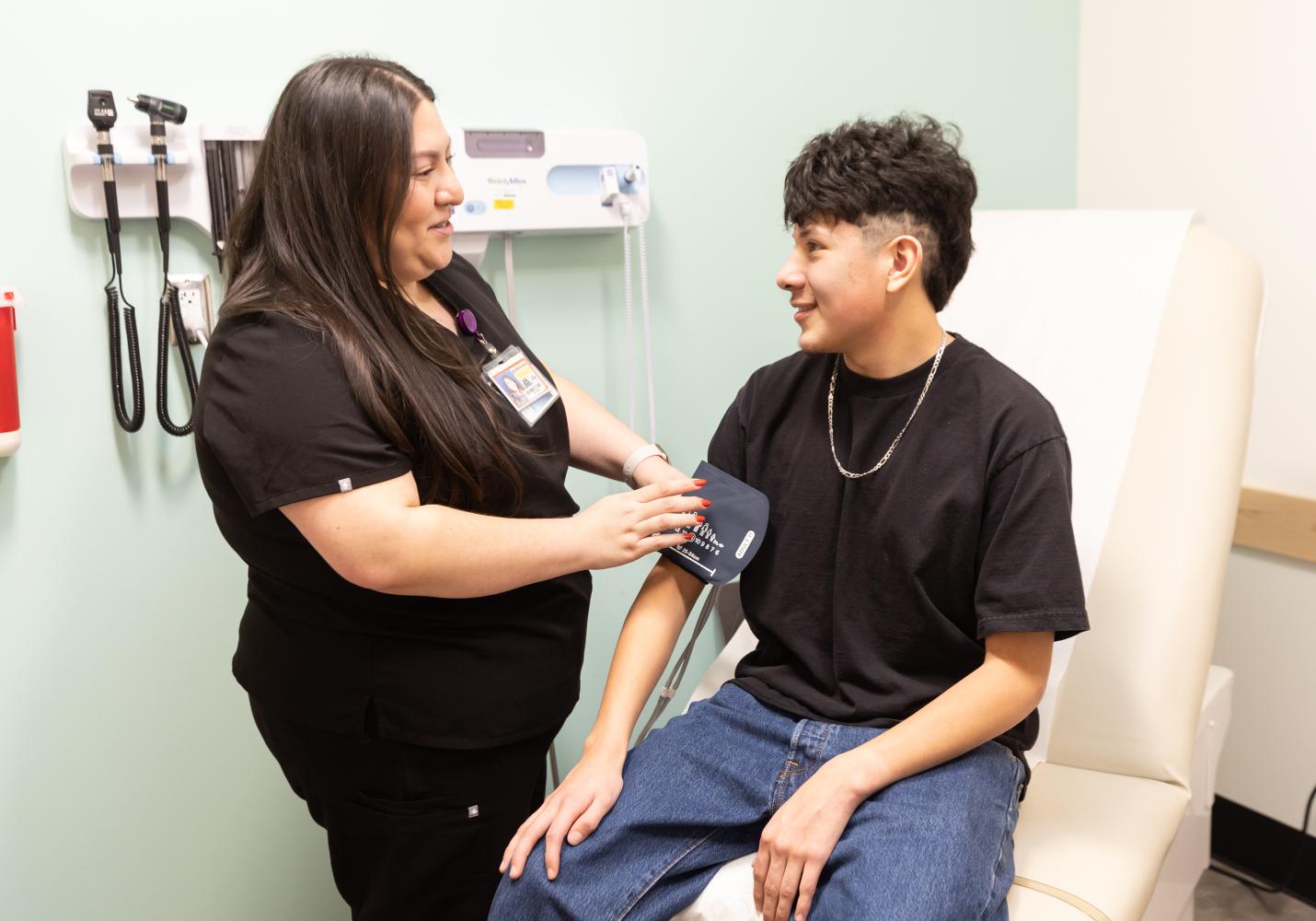 A health team member checks a teenager's blood pressure during a visit at a Student Health Center.