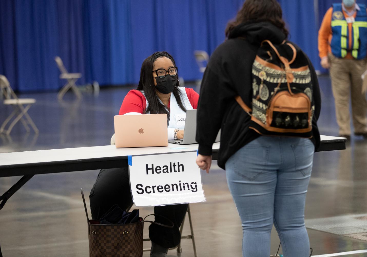 A volunteer helps a community member check in for a health screening.