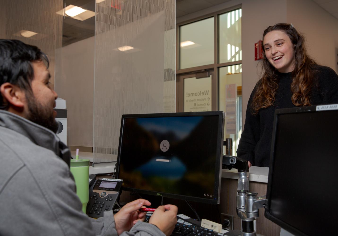 A team member greets a patient checking in for a clinic visit.