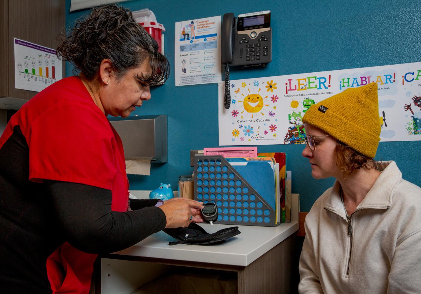 A nurse shows a patient how to use a blood glucose monitor. 