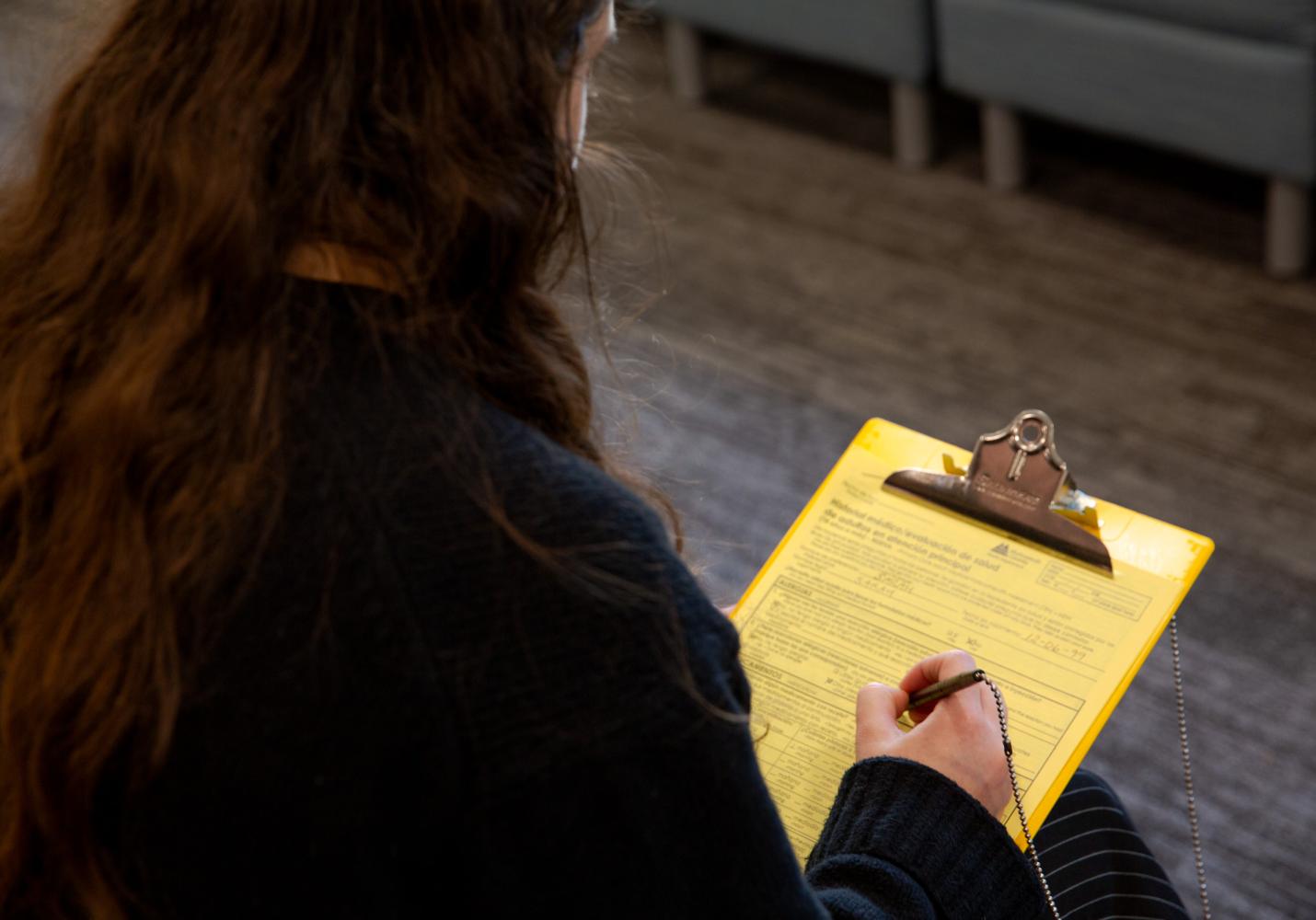 A patient fills out paperwork on a clipboard.