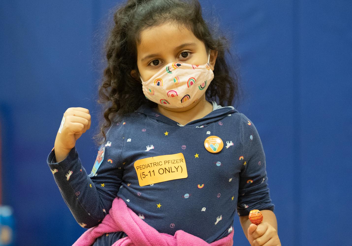 A female child shows off the vaccine she received 